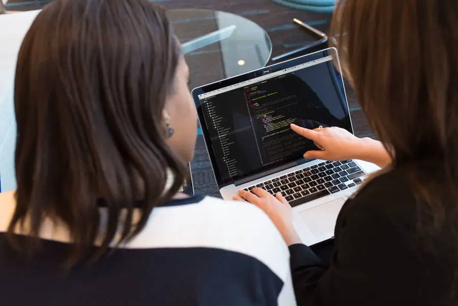 Two developers reviewing code on a laptop